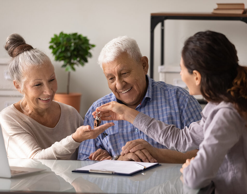 smiling couple taking keys from real estate agent in office